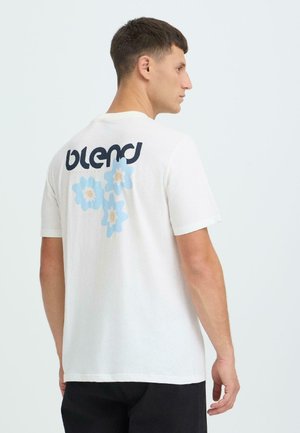 Wit katoenen T-shirt met een "blend"-logo in zwart en drie lichtblauwe bloemen op de achterkant. Korte mouwen en een ontspannen pasvorm.