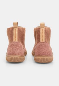 Botines de tobillo de fieltro rosa con material texturizado, suelas de goma y un lazo trasero para ponérselos fácilmente. Presentan un acento de cuero liso en la parte posterior.