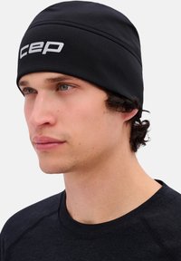 Zwarte muts met een gestructureerde afwerking en een wit "CEP"-logo aan de voorkant. Het ontwerp heeft een nauwsluitende pasvorm en gladde naden.