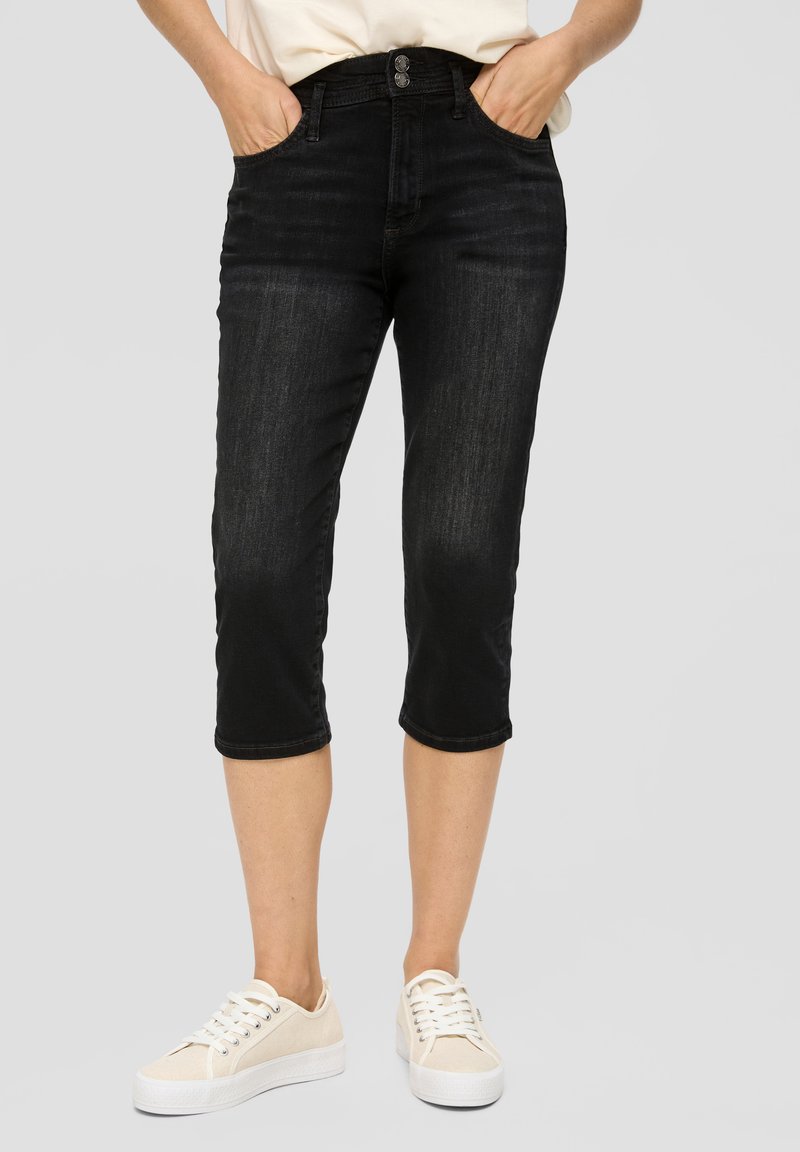 Zwarte denim capri-broeken met zijzakken, een knoopsluiting en een lichte vervaging, gecombineerd met beige veterschoenen.