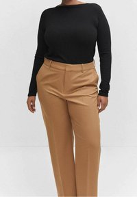 Haut noir à manches longues côtelé associé à un pantalon taille haute beige ajusté, avec une texture lisse et une coupe classique.