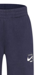 Navyblauwe trainingsbroek van zacht materiaal, met een elastische tailleband en een diagonaal wit Nike-logo op het onderbeen.