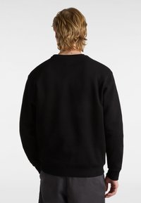 Felpa nera con collo rotondo, polsini e orlo a coste, realizzata in un tessuto morbido con una texture liscia e con un marchio minimale sul retro.