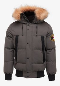 Puffer jacket in gray with a detachable tan fur-lined hood, front buttons, side pockets with black accents, and ribbed cuffs.