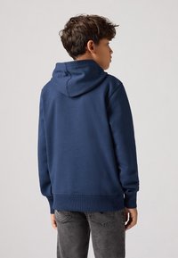 Sweatshirt à capuche bleu marine en tissu texturé, avec des manches et une ourlet côtelés. Dispose d'une poche kangourou et d'un design à coupe décontractée.