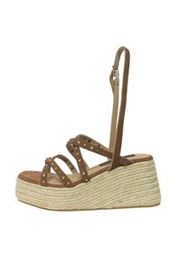 Sandali in suede marrone con plateau, dotati di molteplici cinturini intrecciati e decorati con borchie tonde, e un tacco a cuneo in juta intrecciata.