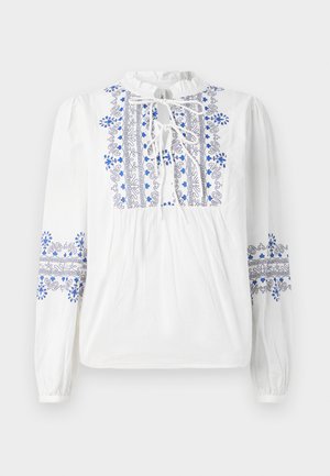 Valkoinen paita, jossa on sinistä ja mustaa kirjontaa kauluksessa ja hihoissa. Ominaisuuksiin kuuluu nauhakiinnitys ja koottu rintaosa. Pitkät, elastiset hihat.