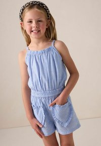 Combinaison bleu et blanche à rayures avec une taille cintrée, des poches en forme de cœur et des bretelles fines. Présente un tissu texturé et des détails élastiques.