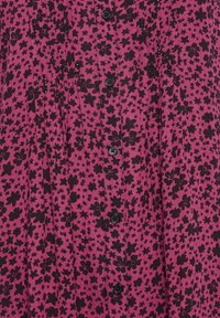 Tissu violet avec motifs floraux et étoiles noirs, boutons noirs au centre et plis verticaux subtils.