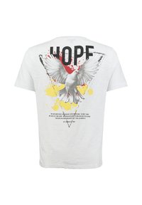 Camiseta blanca con una gran paloma gris en vuelo, salpicaduras de pintura roja y amarilla, y la palabra "ESPERO" en letras negras en negrita en la parte posterior.