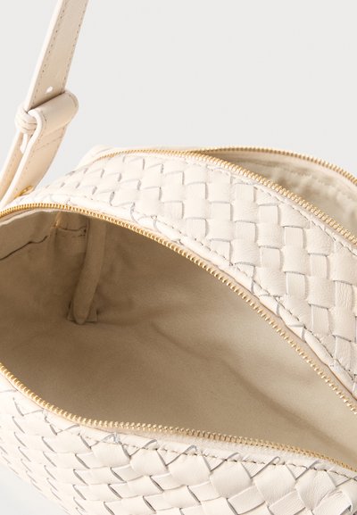 Μπεζ υφασμάτινη τσάντα χιαστί από δέρμα με χρυστό φερμουάρ, ανοιχτή για να δείξει απαλό υφασμάτινο εσωτερικό και ρυθμιζόμενο λουράκι