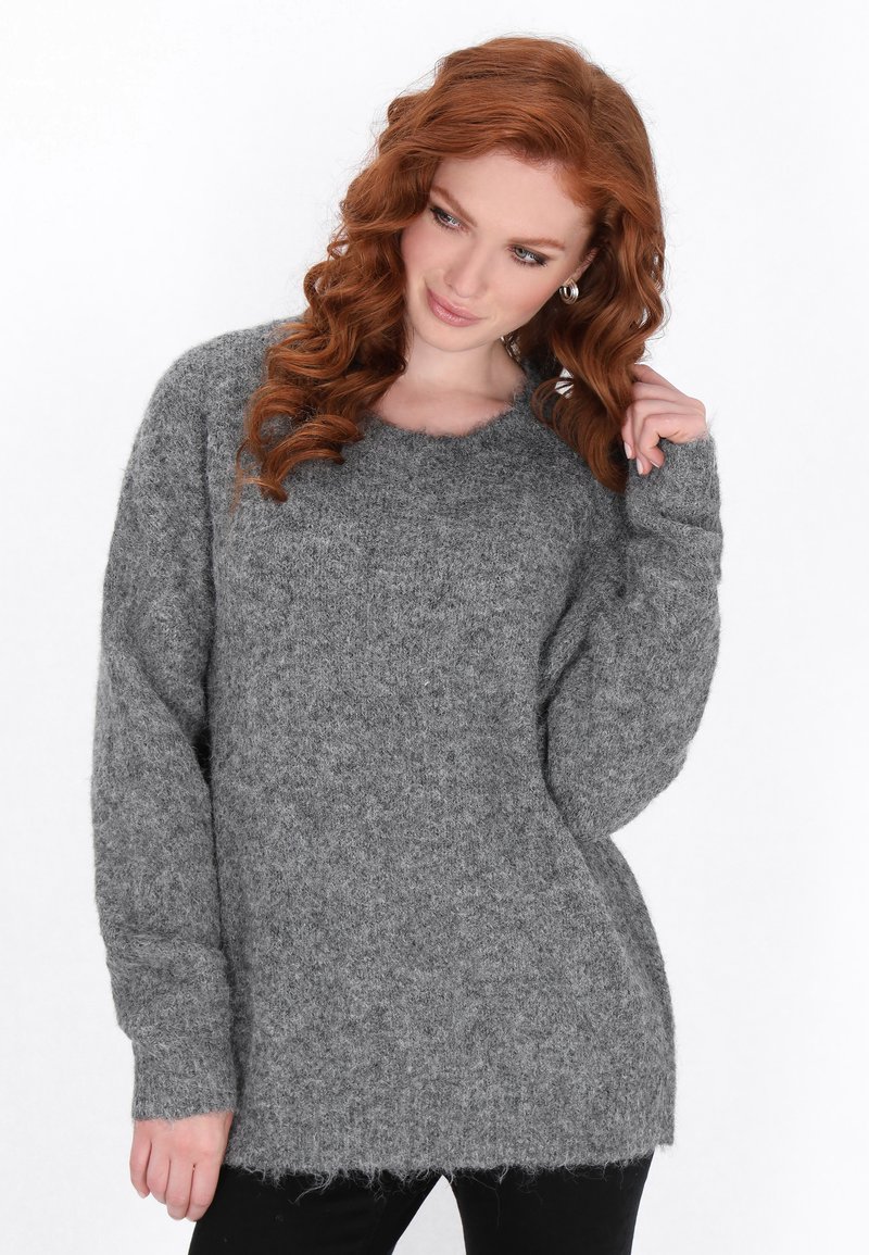 Grauer Strickpullover mit lockerer Passform, weiten Ärmeln, gerippten Bündchen und einem leicht ausgefransten Saum. Weiches, strukturiertes Wollmaterial.