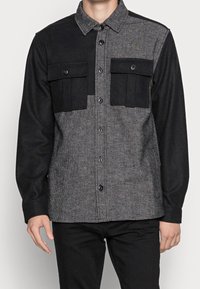 Sort og gråternet flannel skjorte med knaplukning, brystlommer og kontraststoffpaneler. Blød tekstur, skræddersyet design.