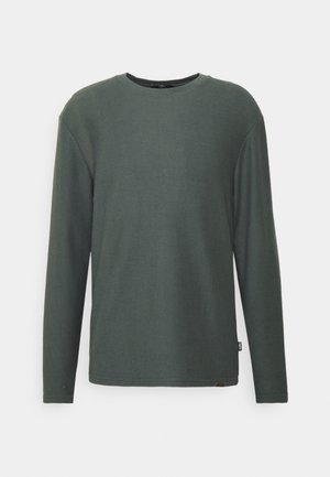 Langärmliges, geripptes T-Shirt mit Rundhalsausschnitt in Dunkelgrün. Weiche Textur mit lockerem Schnitt. Verfügt über ein kleines Markenzeichen am Saum.