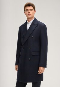 Dunkelblauer, zweireihiger Mantel mit texturiertem Muster, Reverskragen und sechs schwarzen Knöpfen, mit Seitentaschen und tailliertem Schnitt.