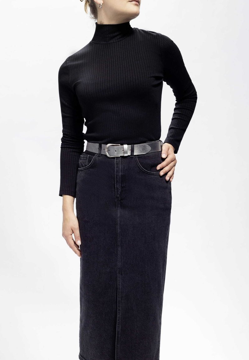 Svart ribbad polotröja som matchas med en högmidjad kjol i mörk denim. Outfiten kompletteras av ett texturerat silverbälte.