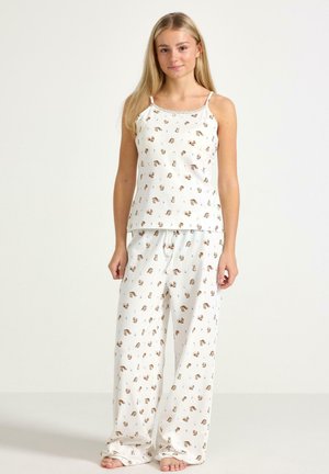Lekki, biały bawełniany komplet piżamowy z powtarzającym się nadrukiem zwierząt. Top na ramiączkach ma cienkie paski, a spodnie posiadają elastyczną talię.