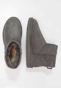 Harmaat mokkanahka nilkkakengät, joissa on pehmeä turkisl lining, litteä kumipohja ja koristeellinen sivuompelu. Pyöristetty kärki ja liukusn design.