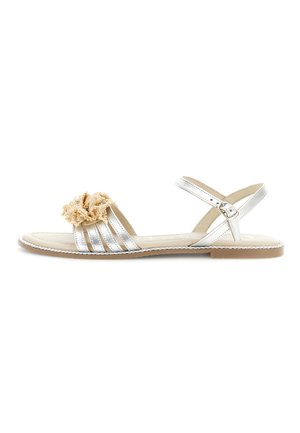 Sandalo piatto argento con cinturino alla caviglia, chiusura con fibbia e decorazione floreale beige sulle cinghie anteriori, con suola beige e bordi rifiniti.