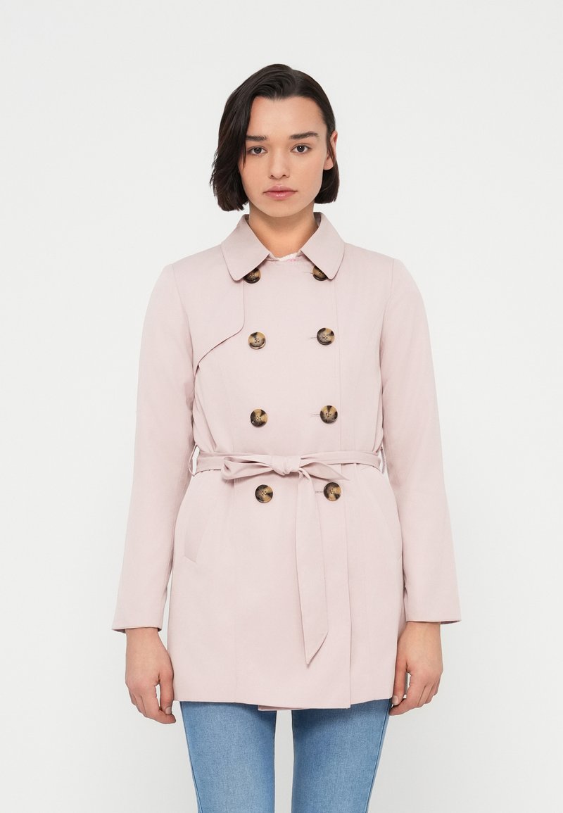 Ροζ ανοιχτό ροζ καπαρντίνα με διπλό πέτο, κουμπιά σε ταμπά απόχρωση, ζώνη στη μέση και τσέπες στα πλάγια. Ομαλό ύφασμα με γιακά και μακριά μανίκια.