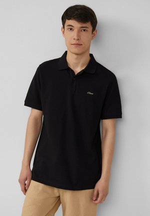 Schwarzes Poloshirt aus Baumwolle, mit klassischem Kragen und kurzen Ärmeln. Goldenes Logo-Detail auf der linken Brust.