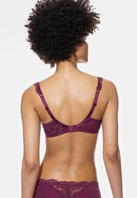 Rintaliivi viininpunaisella pitsireunalla, säädettävillä harteilla, kukkakuosisella ja hakaskiinnityksellä, joka näyttää sileän selkäosan ja tekstuurin kankaan.