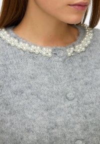 Light gray knit cardigan with pearl embellishments around the collar and front buttons, featuring a soft texture and a round neckline.