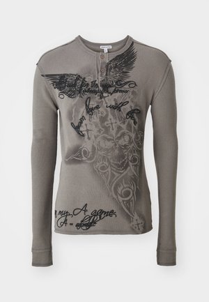 Long-sleeve, gray henley shirt made of ribbed fabric. Features black printed graphics and text, including wing and skull designs.