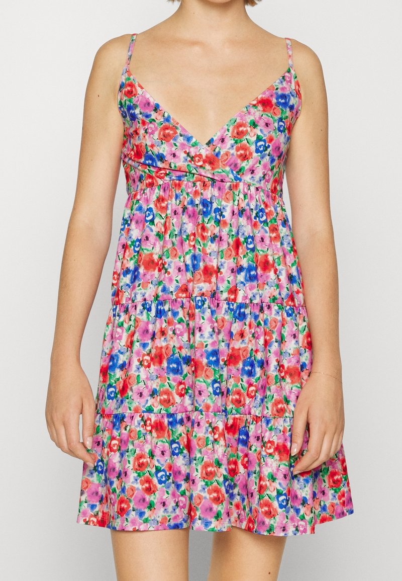 Robe fleurie sans manches avec fines bretelles et col en V, affichant un motif multicolore en rouge, rose, bleu et vert.