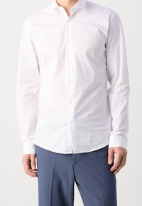 Witte, lange mouwen overhemd met een button-down kraag en een gladde textuur, gecombineerd met blauwe, op maat gemaakte broek. Minimalistisch ontwerp.