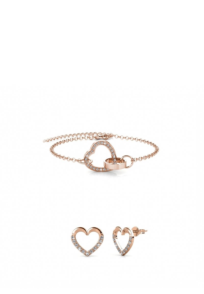 Set di gioielli in oro rosa composto da un bracciale a forma di cuore con gemme trasparenti e orecchini a bottone a forma di cuore coordinati. Finitura metallica liscia, catena delicata.