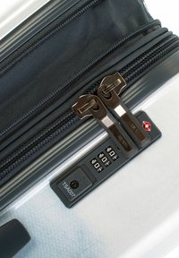 Black zipper with dual pulls, located on a gray hard-shell suitcase. Includes a TSA-compliant lock and combination dials on a textured surface.