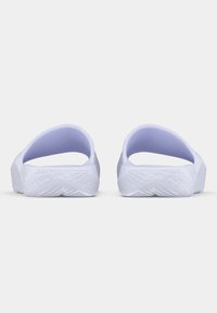 Λευκά πέδιλα με κλειστή μύτη και υφή από καουτσούκ στην σόλα, με απαλή μωβ επένδυση στο εσωτερικό των λουριών, διαθέτοντας σχεδίαση προσαρμοσμένη για άνεση.