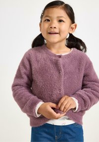 Paarse pluizige cardigan met ronde halslijn, knoopsluiting en lange mouwen. Draag over een wit longsleeve shirt met bloemenpatroon.