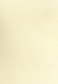 Κοντινή λήψη κρεμ υφάσματος με ραβδώσεις, κάθετες υφασμένες γραμμές που δημιουργούν ένα κυματιστό μοτίβο.