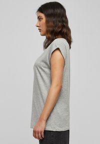 T-shirt grigia a maniche corte con una vestibilità ampia. Realizzata in tessuto morbido e strutturato. Presenta maniche arrotolate e orlo dritto.