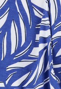 Tissu bleu et blanc présentant un motif de feuilles avec des contours noirs, matériau en coton texturé en vue rapprochée.