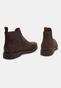 Bottines Chelsea en cuir brun avec panneaux latéraux élastiques, détails de broguage et languettes. Bout arrondi et semelles en caoutchouc durables pour plus de stabilité.