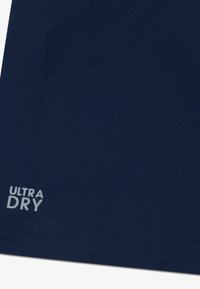 Ύφασμα σε ναυτικό μπλε με υφασμένο μοτίβο που έχει τυπωμένη τη φράση "ULTRA DRY" σε λευκό. Το υλικό φαίνεται ελαφρύ και διαπνέον.