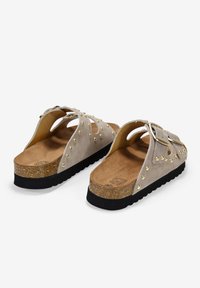 Sandalias de ante en gris claro con tachuelas doradas, una hebilla ajustable y una media suela de corcho. Suela de goma negra texturizada para mayor agarre.