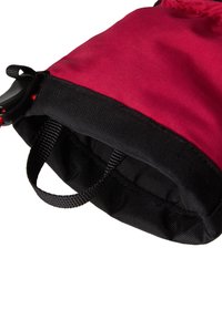 Rdeča in črna tkaninska torba z gladkim zunanjim površjem, ki ima črno ročajno naramnico in prilagodljiv zadrževalni mehanizem, s sodobno, kompaktno zasnovo.