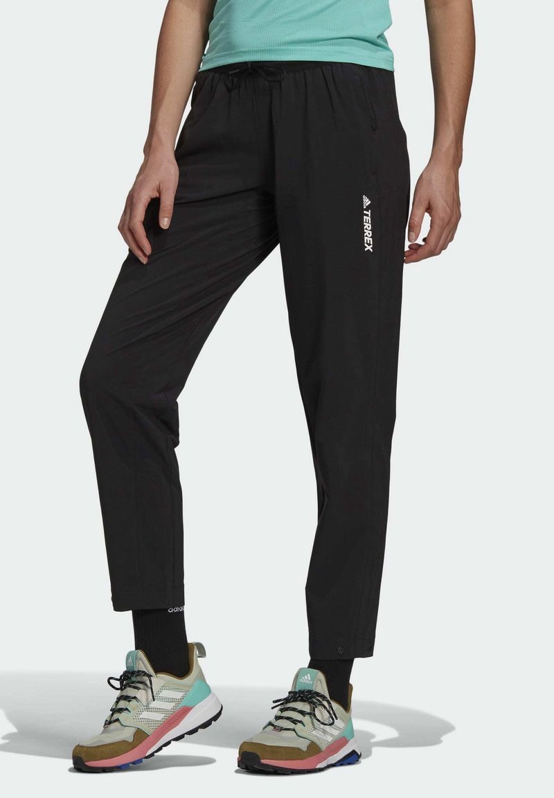 Pantalones ligeros, impermeables y negros con cintura ajustable y diseño acampanado, que cuentan con un logotipo blanco de "TERREX" en el muslo izquierdo.