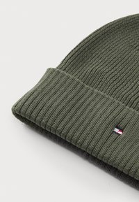 Zielony, ribbed beanie z podwiniętym mankietem i małą naszywką z logo w czerwono-biało-niebieskich detalach. Miękka struktura i elastyczne dopasowanie.