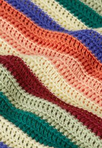 Flerfärgad virkade tyg med horisontella ränder i lila, röd, orange, gul, grön och krämfärgad. Texturerad, öppen vävdesign.