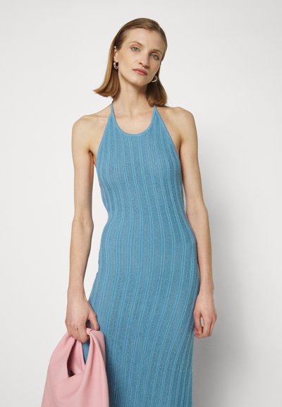 Robe bleu à col halter côtelé avec un tissu texturé. Présente une silhouette cintrée et une finition lisse. Accessoire : sac à main rose pâle.