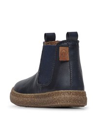 Bottines en cuir marine avec panneaux latéraux élastiques, semelle en caoutchouc marron texturée et patch logo marron à l'arrière. Fini lisse dans l'ensemble.