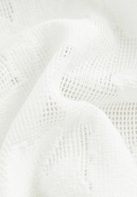 Tissu blanc transparent avec une texture ouverte, semblable à un filet, présentant des motifs de grille irréguliers. Doux et léger, idéal pour le superposé ou le drapé.