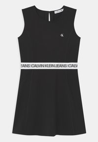 Czarna sukienka bez rękawów z dopasowaną górą i rozkloszowanym dołem. Posiada białą elastyczną talię z nadrukiem "CALVIN KLEIN JEANS". Gładka tekstura.
