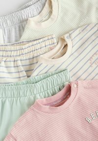 Collectie van lichte, gestreepte tops en broeken in pastelkleuren; met elastische taillebanden, drukknoopjes en gebreide texturen.