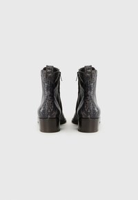 Botas de tobillo de cuero con un patrón de serpiente oscuro. Cuentan con una cremallera lateral y un tacón bajo tipo bloque. Material texturizado con acentos suaves.